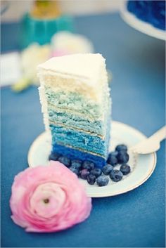 a piece of cake on a plate with blueberries and raspberries