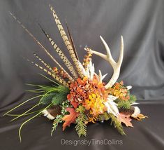 an arrangement of flowers and antlers is displayed on a black background in front of a gray backdrop