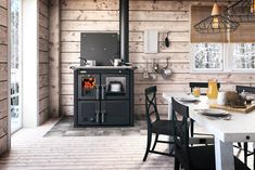 an old fashioned stove in a rustic kitchen with wood paneling and white tablecloths