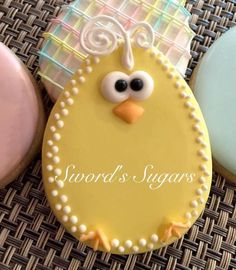 there is a cookie decorated like a bird on the table next to some frosted cookies