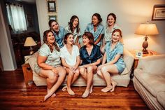 a group of women sitting next to each other on top of a couch in front of a lamp