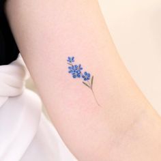 a small blue flower tattoo on the arm