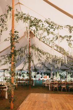 Wedding under sailcloth tent with hanging smilax vine greenery and white wisteria flowers Tent With Chandelier Outdoor Weddings, Tent Engagement Decorations, Vintage Tent Wedding, Decorating A Wedding Tent, Forest Tent Wedding, Whimsical Tent Wedding, Wildflower Tent Wedding, Bell Tent Wedding, Colorful Tent Wedding