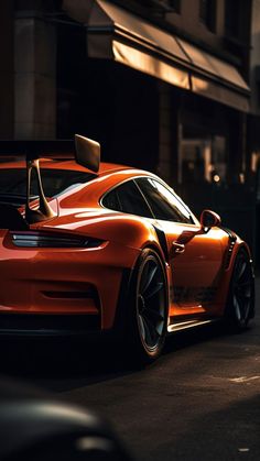 an orange sports car parked on the side of the road in front of a building