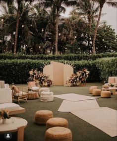 an outdoor area with lots of furniture and flowers on the ground, surrounded by palm trees