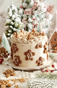 a decorated cake sitting on top of a table next to christmas trees and cookies in the snow