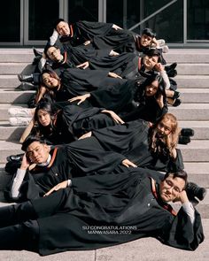 a group of people in graduation gowns laying on the ground next to each other