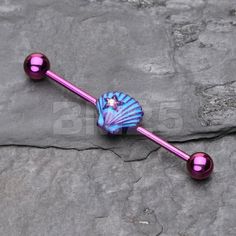 a pink and blue glass belly button with two balls on it's end, resting on a rock