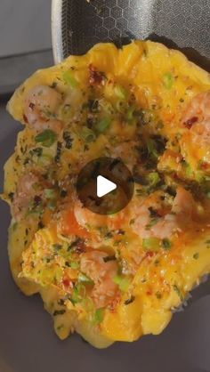 an omelet with shrimp and vegetables in it on a plate next to a frying pan