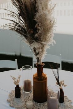 there is a vase with some feathers in it and two candles are on the table