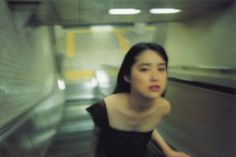 a woman in black dress riding an escalator with her hand on her hip