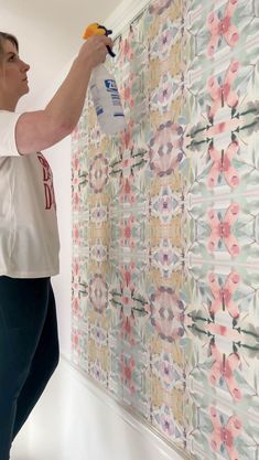 a woman in white shirt painting wallpaper with rollers