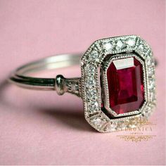 an engagement ring with a red stone surrounded by diamonds