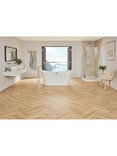 a bathroom with wood flooring and white bathtub next to a large open window