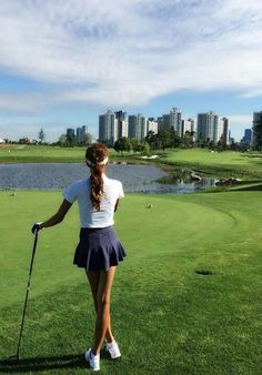 a woman standing on top of a lush green field next to a golf ball court