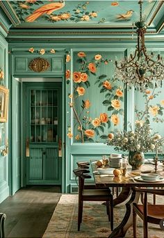 a dining room with green walls and flowers on the wall