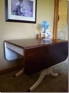 a wooden desk sitting in front of a framed photo on the wall next to a mirror