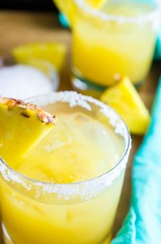 two glasses filled with pineapple margaritas sitting on top of a table