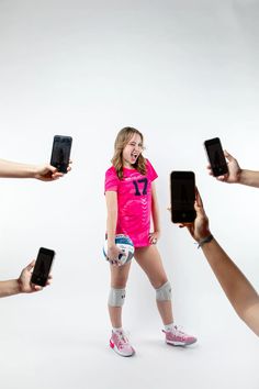 a girl in pink shirt holding up cell phones