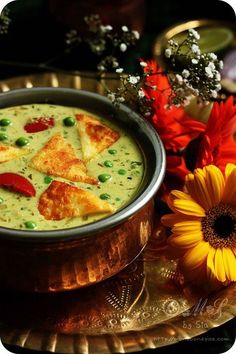 a metal bowl filled with food next to a yellow flower