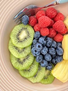 a bowl filled with different types of fruit and a fork on top of the bowl