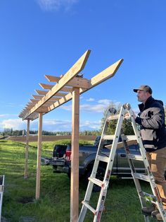 a man standing on a ladder next to a wooden structure