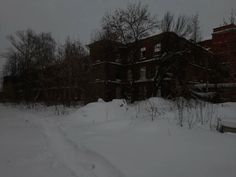 a snow covered road in front of an old brick building