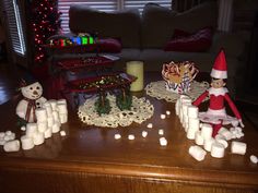 some marshmallows and candles on a table in front of a christmas tree