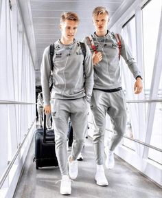 two men in grey tracksuits walking down a hallway