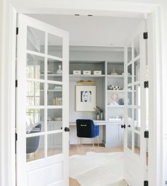 an open door leading into a home office with white walls and wood floors, along with a rug on the floor