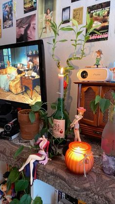 a table topped with a tv next to a potted plant and a candle on top of it