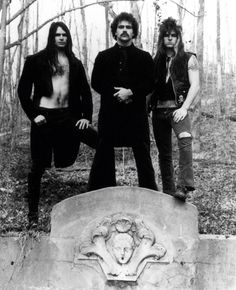 three men standing next to each other in front of a grave with an animal head on it