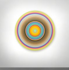 an abstract painting with multicolored circles on a white wall in the middle of a room