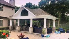 an outdoor living area with patio furniture and flowers on the ground in front of it