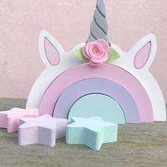 a wooden toy with a pink flower on top and a unicorn horn next to it