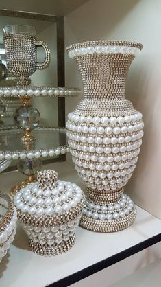 three vases with pearls on them are sitting on a shelf in front of a mirror