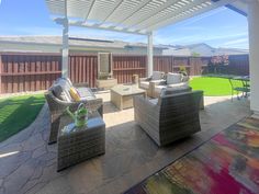 a covered patio with wicker furniture and green grass