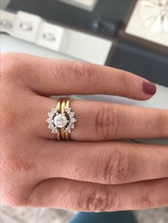 a woman's hand with two gold rings on it and one diamond ring in the middle