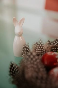 a white rabbit figurine sitting on top of a table next to some fruit