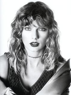 a black and white photo of a woman with long curly hair wearing a choker