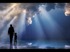 a father and son walking on the beach under a cloudy sky with sunbeams