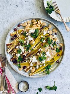 a white plate topped with asparagus and chickpeas next to silverware