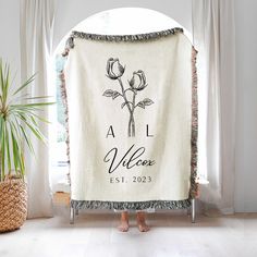 a woman standing in front of a white towel with flowers on it