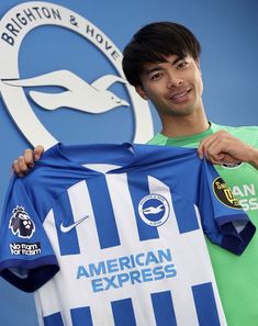 a young man holding up a soccer jersey