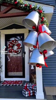 a christmas wreath with bells hanging from the front door and presents on the porch below