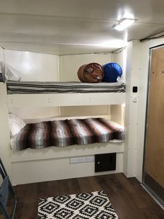 bunk beds in a small room with wooden floors and white walls, along with black and white rugs