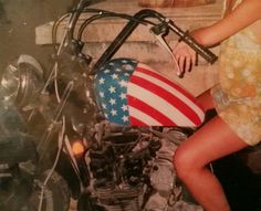 a woman sitting on top of a motorcycle with an american flag painted on the side