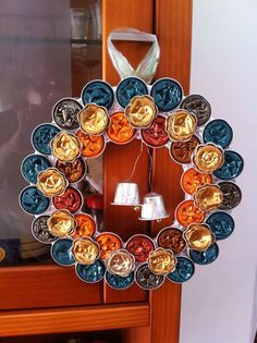 a wreath made out of tin cans sitting on top of a wooden shelf next to a mirror