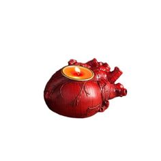 a red heart shaped candle holder with a lit candle in it's center on a white background