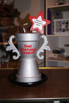 a silver cup with red and white stars on it that says rad mustangs league